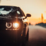 luxurious-car-parked-highway-with-illuminated-headlight-sunset